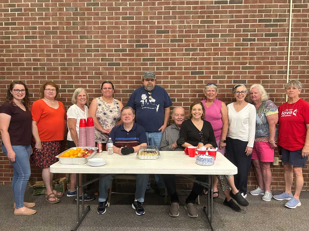 Congregation members standing around a table.